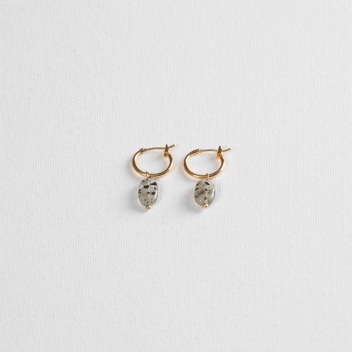 Gold hoop earrings with Dalmatian-like Black Rutilated Quartz Pendants, showcased on a clean white background.
