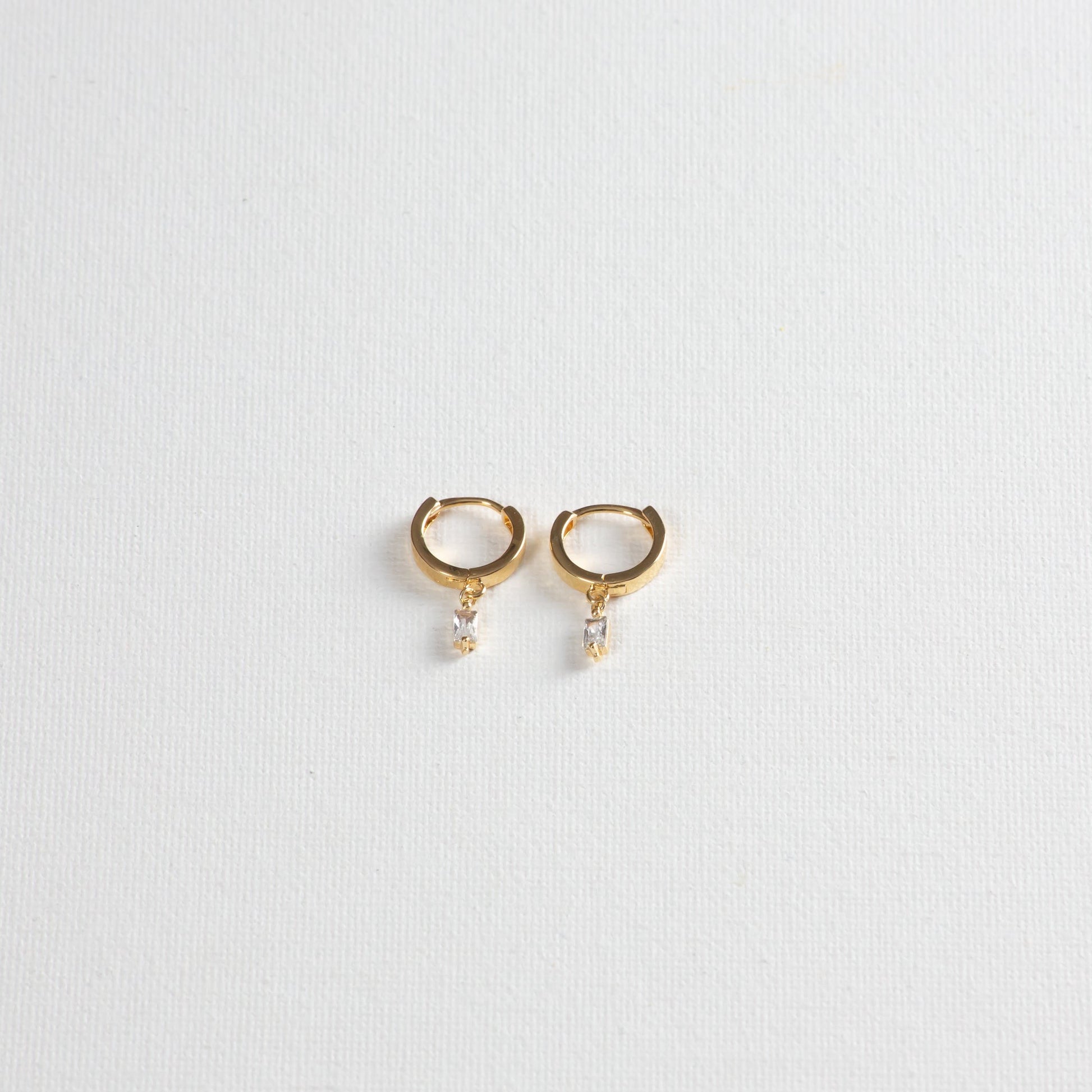 Small hoop earrings with mini baguette crystal charms, showcased on a clean white background.