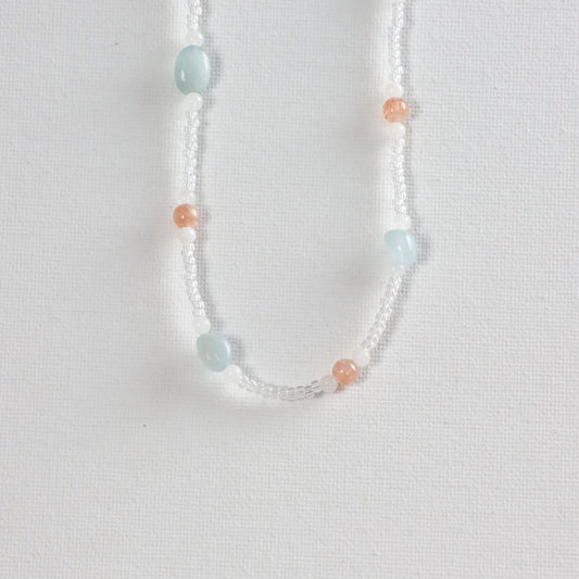 Predominantly clear beads with accents of soft pink and pastel blue glass beads on a white background.