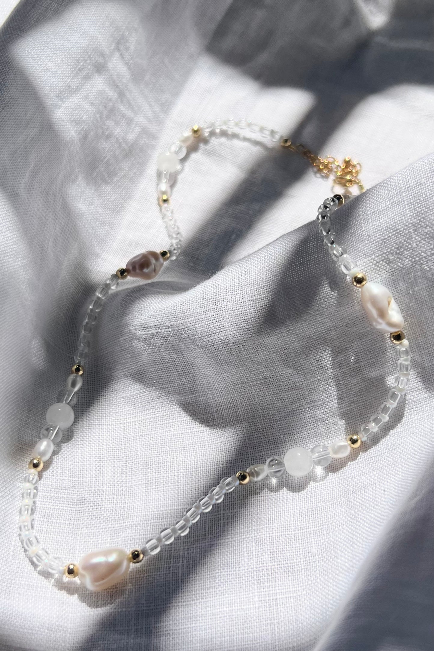 The necklace carefully placed on a textured linen, showcasing the details of the necklace beads.